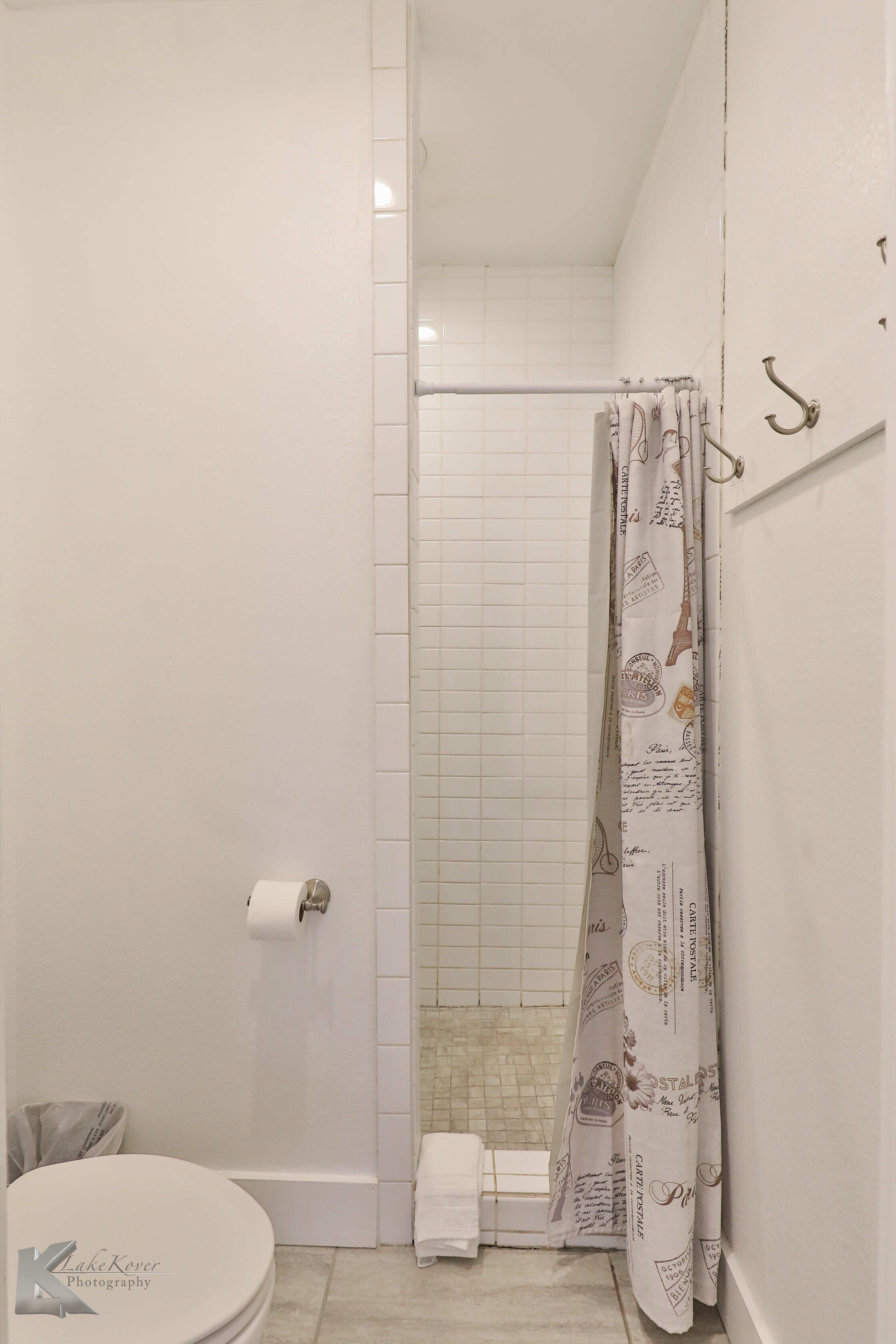 Une salle de bain avec une douche, des toilettes et un porte-serviettes.
