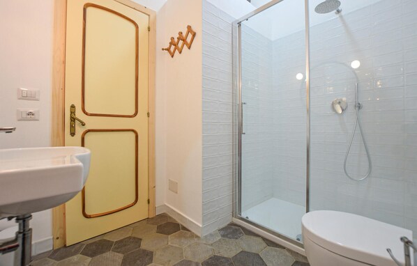 Un baño con ducha acristalada, inodoro y lavamanos.