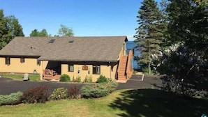 A two-story building with a sloped roof, a front porch, and a small staircase leading to the entrance. - Bayfield Island View Lodging "Sevona Suite" on Lake Superior with Best Lake view (Bayfield)