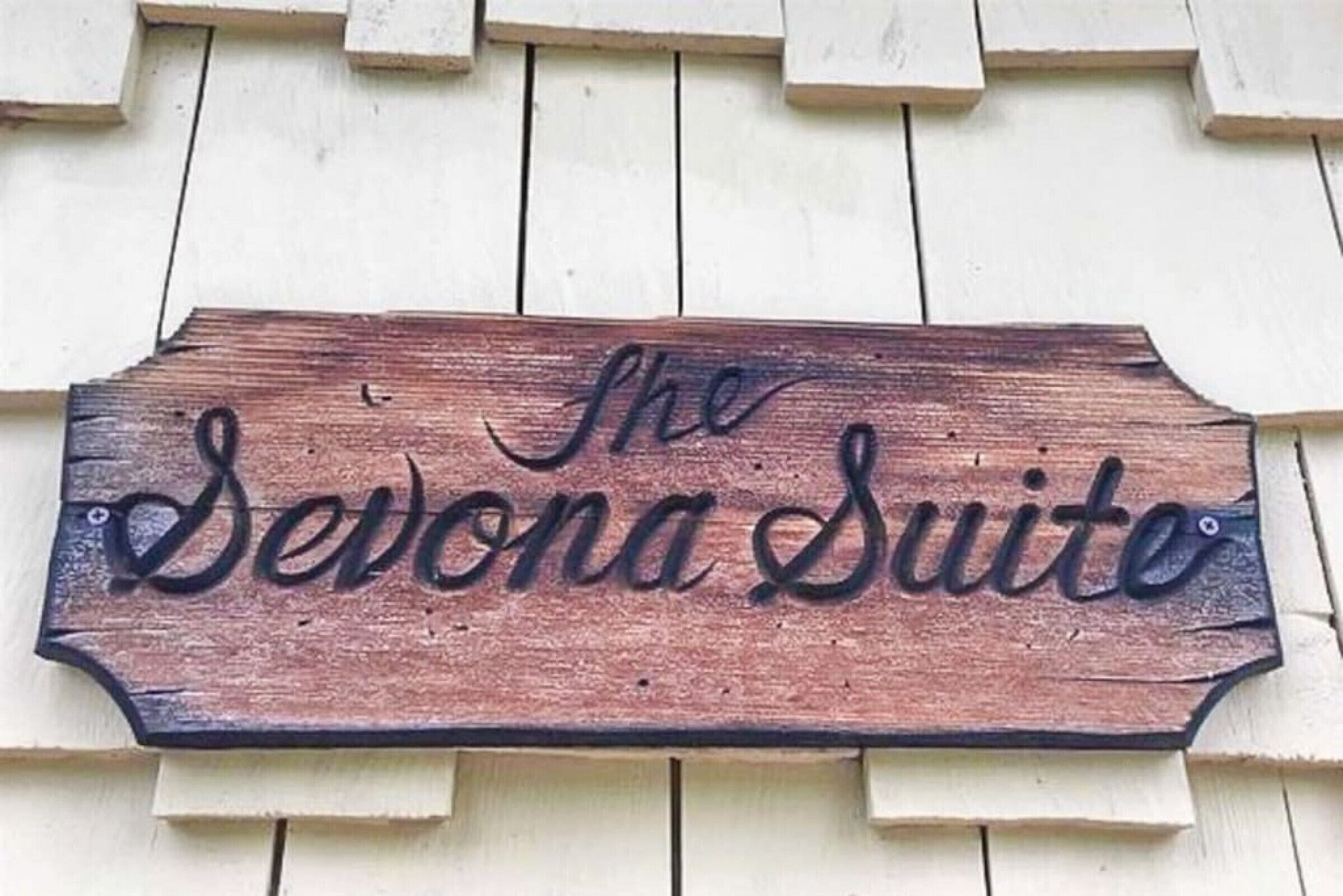 Un cartello di legno con la scritta 'The Sevona Suite' su fondo bianco in legno.
