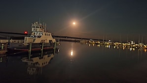 A marina at night with a ferry docked, calm water reflecting lights, and a clear view of the moon. - Bayfield Island View Lodging "Sevona Suite" on Lake Superior with Best Lake view (Bayfield)