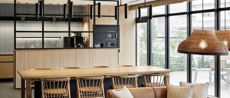 A modern kitchen with a large island, wooden cabinets, and black pendant lights.