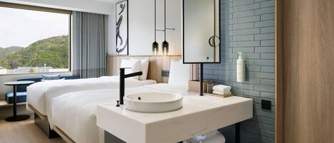 Habitación de hotel moderna con una cama grande, un lavamanos redondo, un espejo y vistas al exterior.
