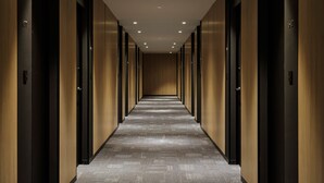 Un pasillo largo y estrecho con paredes y puertas de madera, que conduce a una zona oscura al final.
