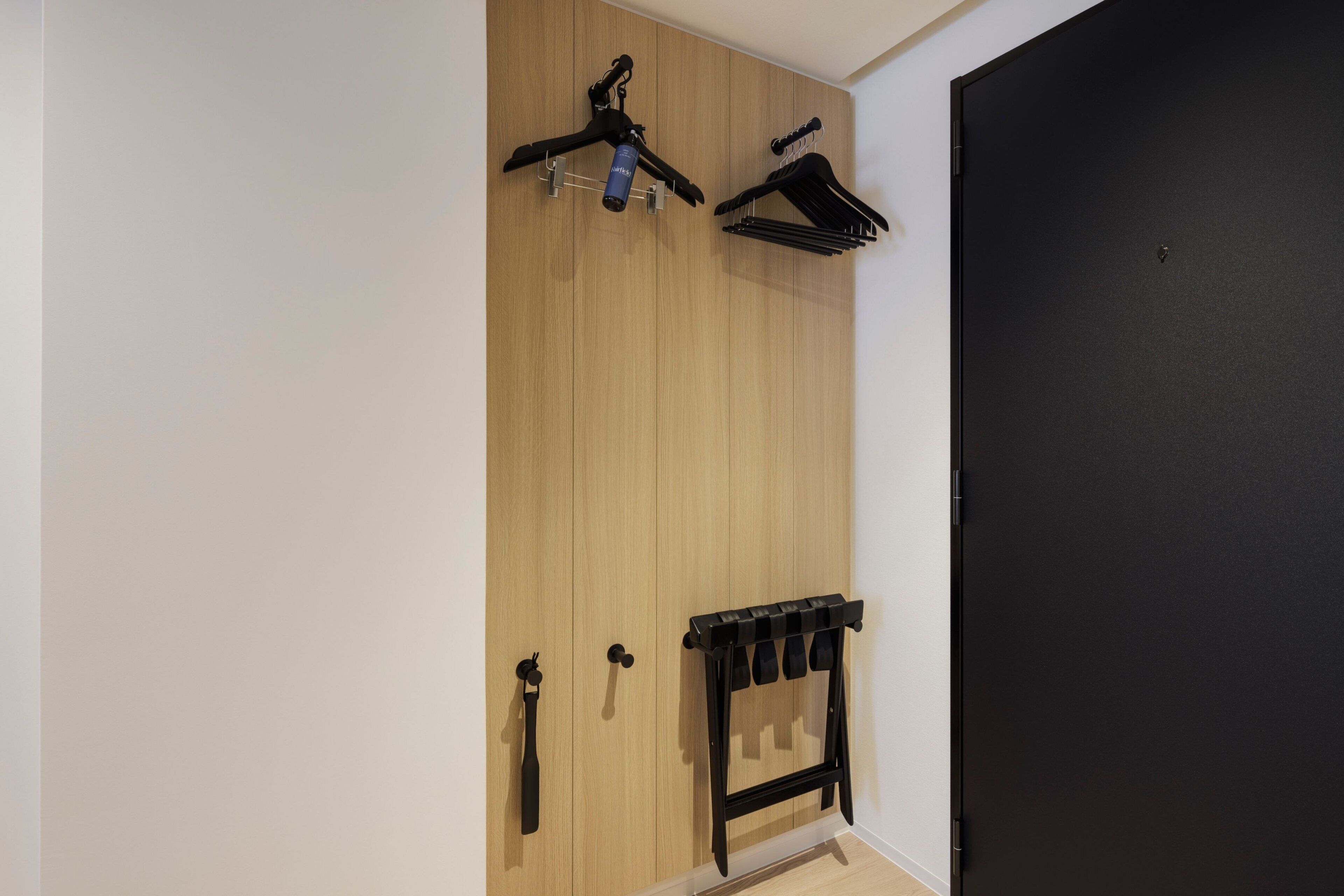 Een kamer met een houten kast, een zwarte deur en een zwart kledingrek met spiegel.