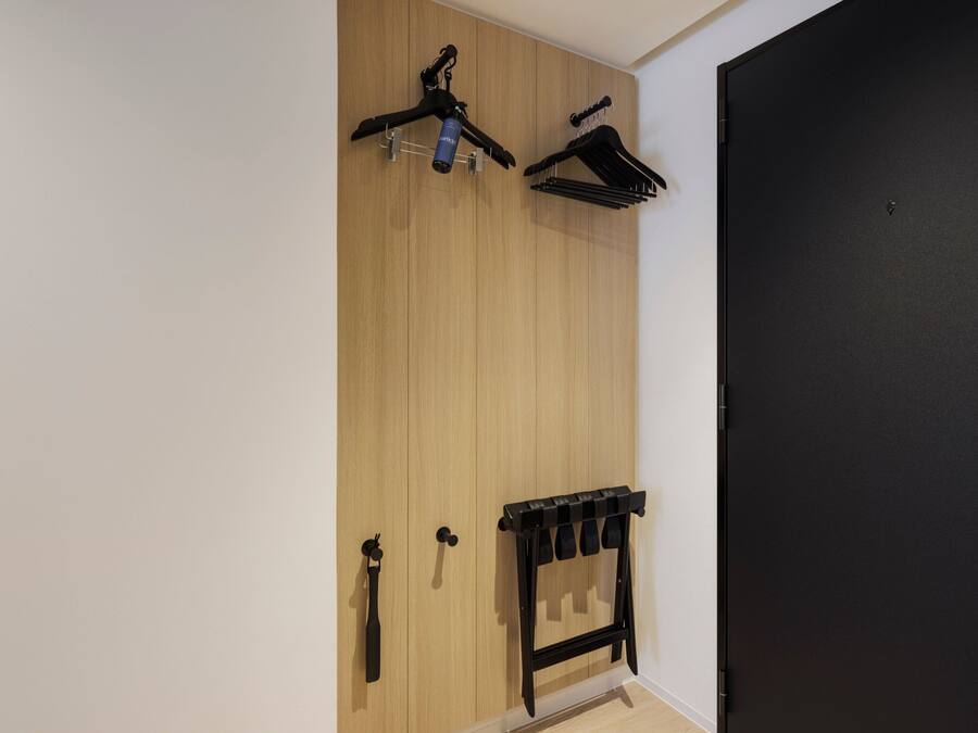 Een kamer met een houten kast, een zwarte deur en een zwart kledingrek met spiegel.