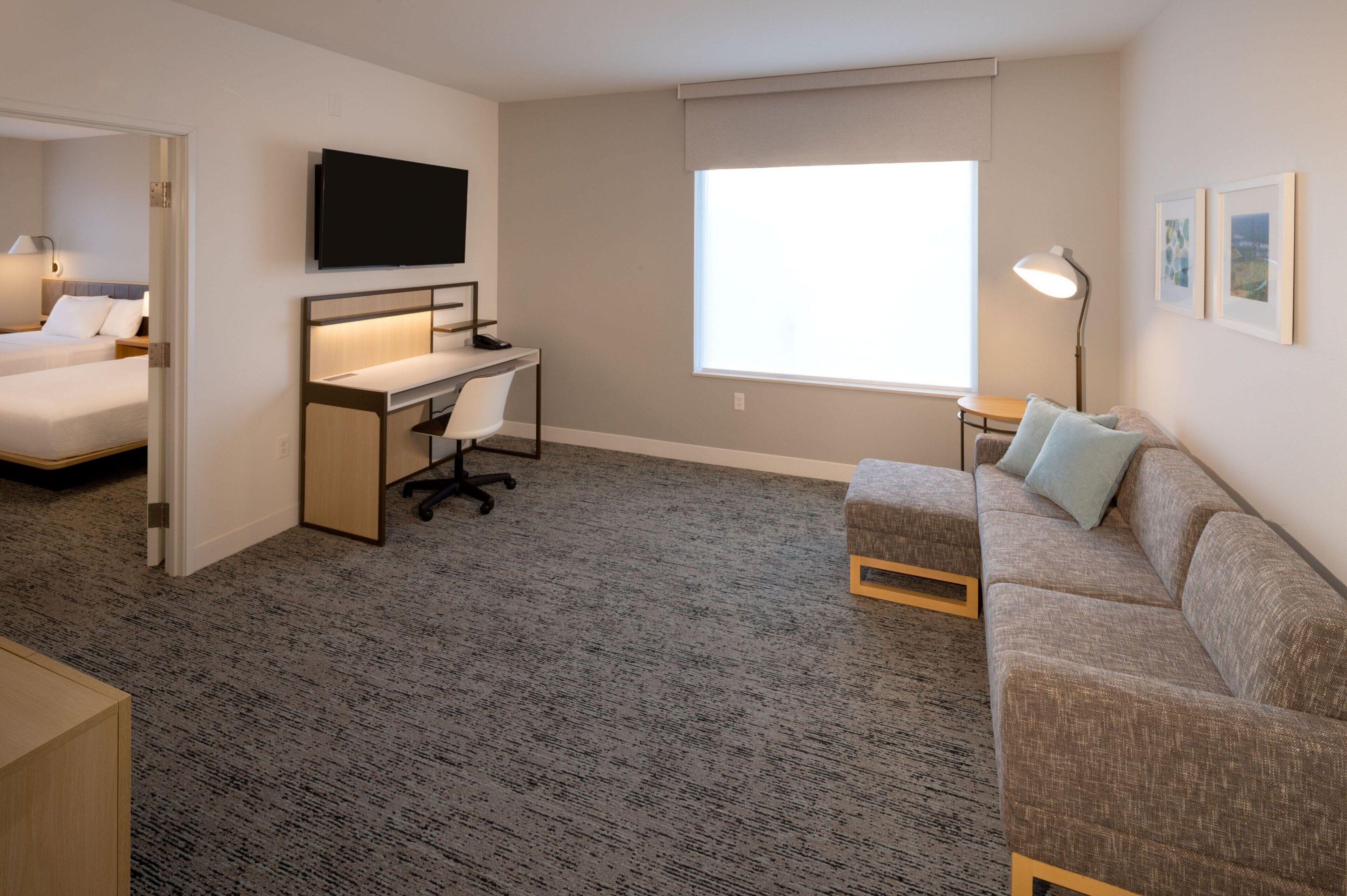 A hotel room with a bed, desk, and sofa.