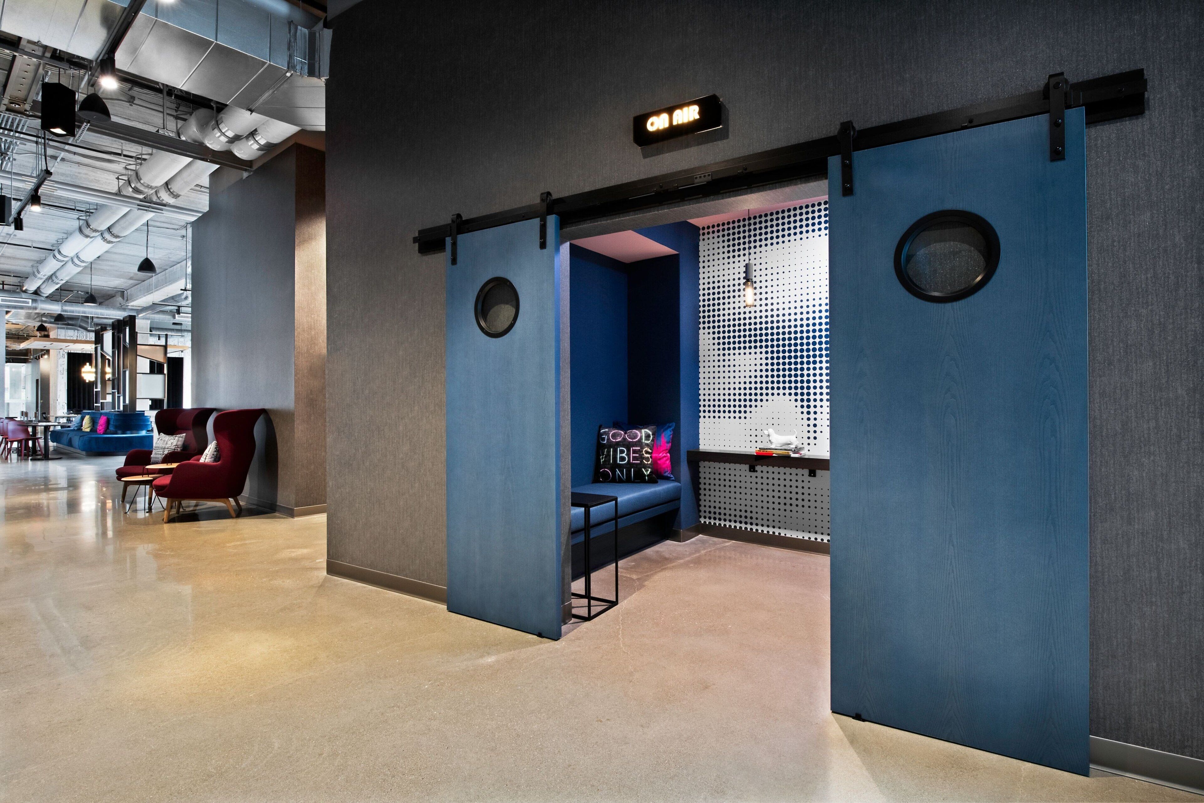 A modern lobby with a blue seating area, a sign indicating air conditioning, and a visible ceiling with exposed ductwork.