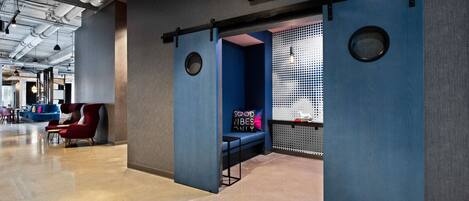 A modern lobby with a blue seating area, a sign indicating air conditioning, and a visible ceiling with exposed ductwork.