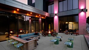 Un espace extérieur aménagé en terrasse, avec un banc en bois, des chaises et un foyer.