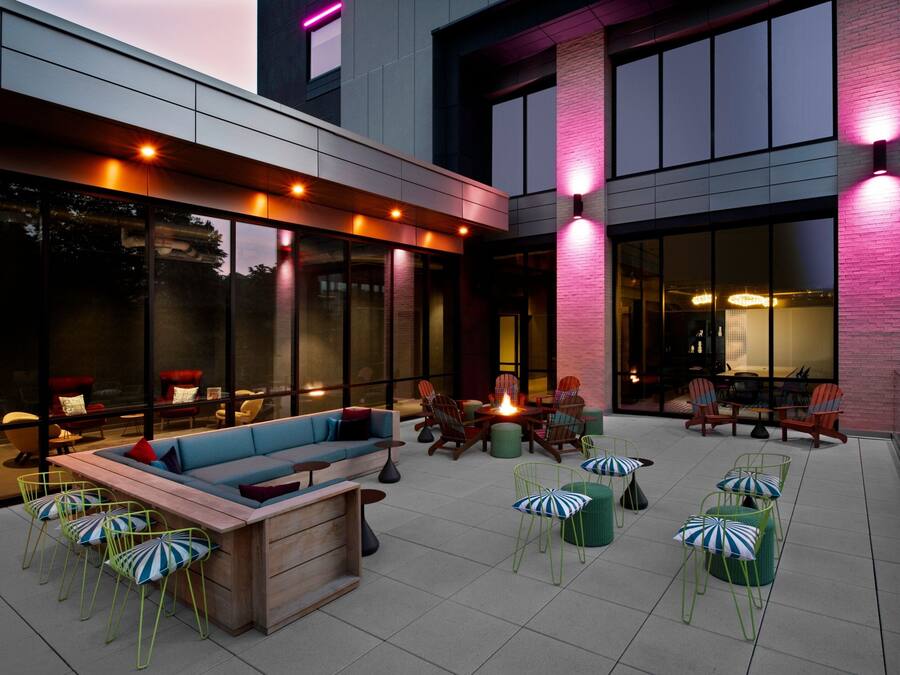 An outdoor patio area with a wooden bench, chairs, and a fire pit.