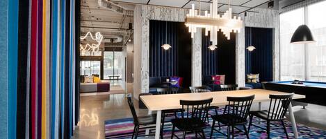 A modern dining area with a long table, black chairs, and a colorful striped rug.