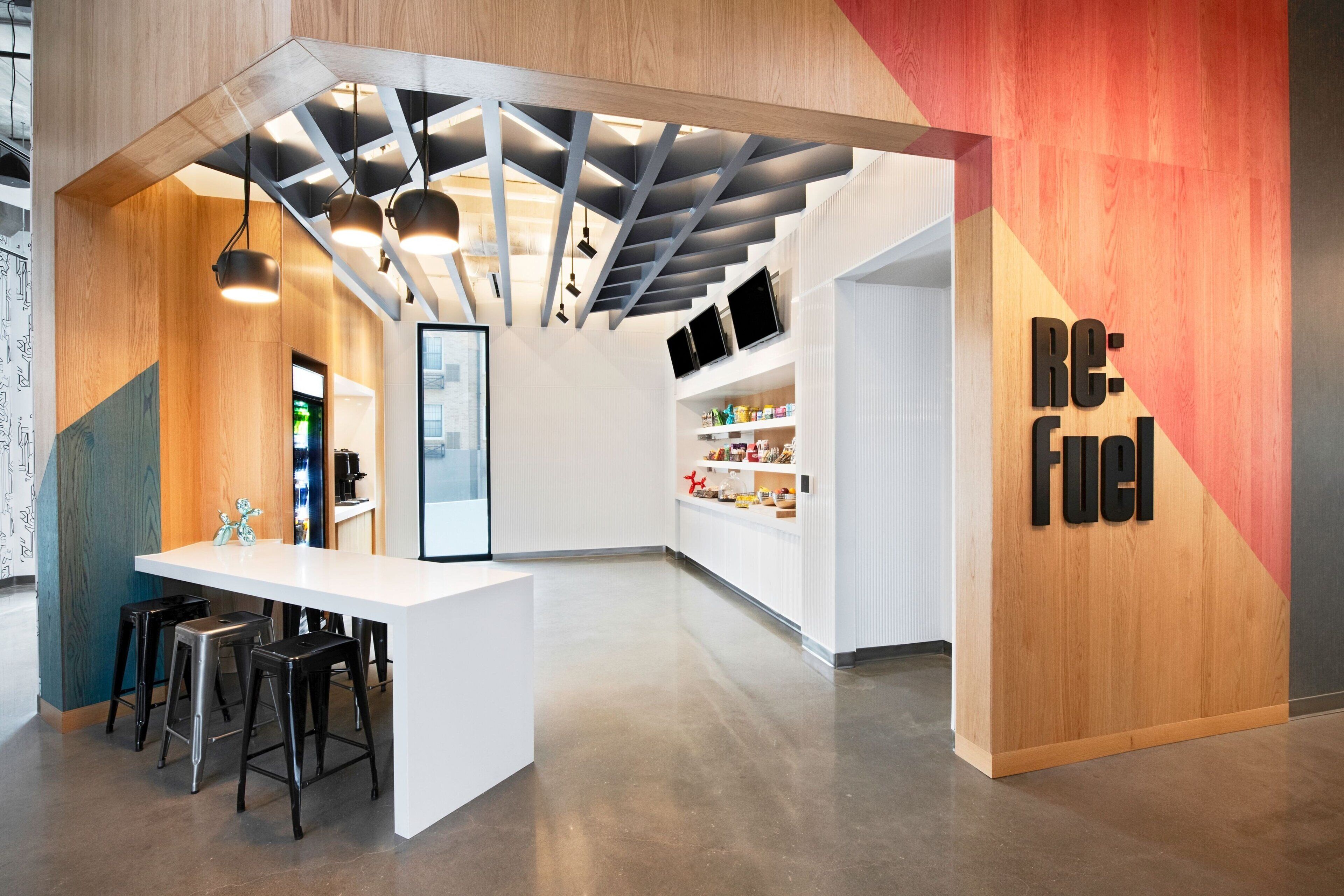 Um interior moderno com um balcão de recepção branco, banquetas de bar e um balcão com prateleiras.