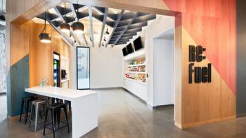 Um interior moderno com um balcão de recepção branco, banquetas de bar e um balcão com prateleiras.