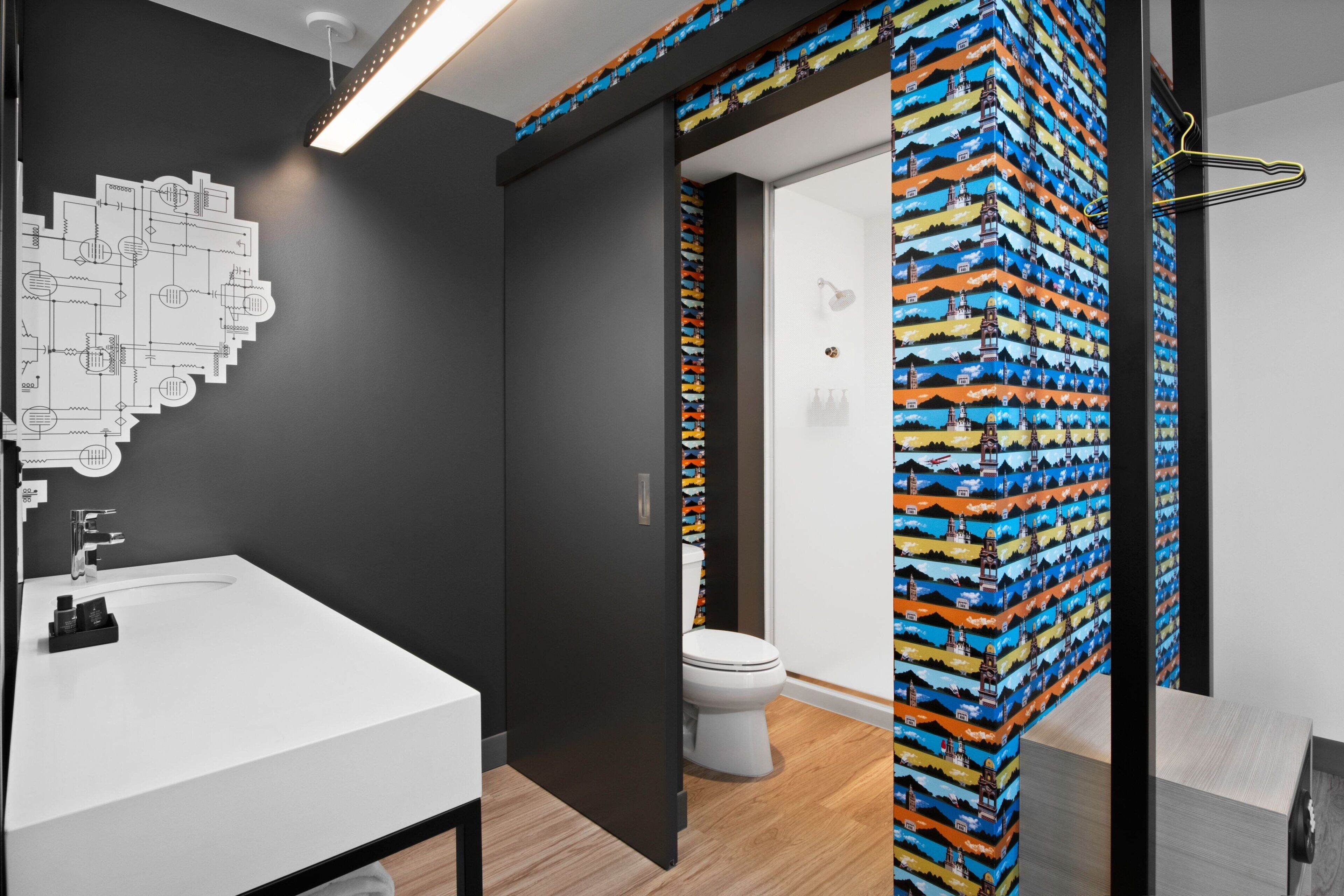 A modern bathroom with a white sink, black walls, and a colorful shower curtain.