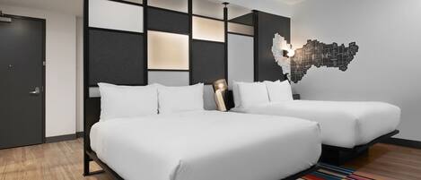 Una habitación de hotel moderna con dos camas, un tapete a rayas de colores y una obra de arte en la pared.