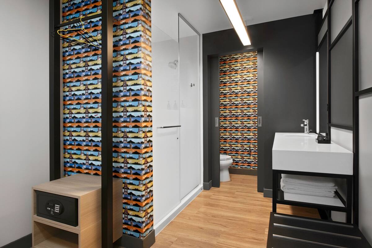 Un baño moderno con suelo de madera, un lavabo blanco y un espejo.