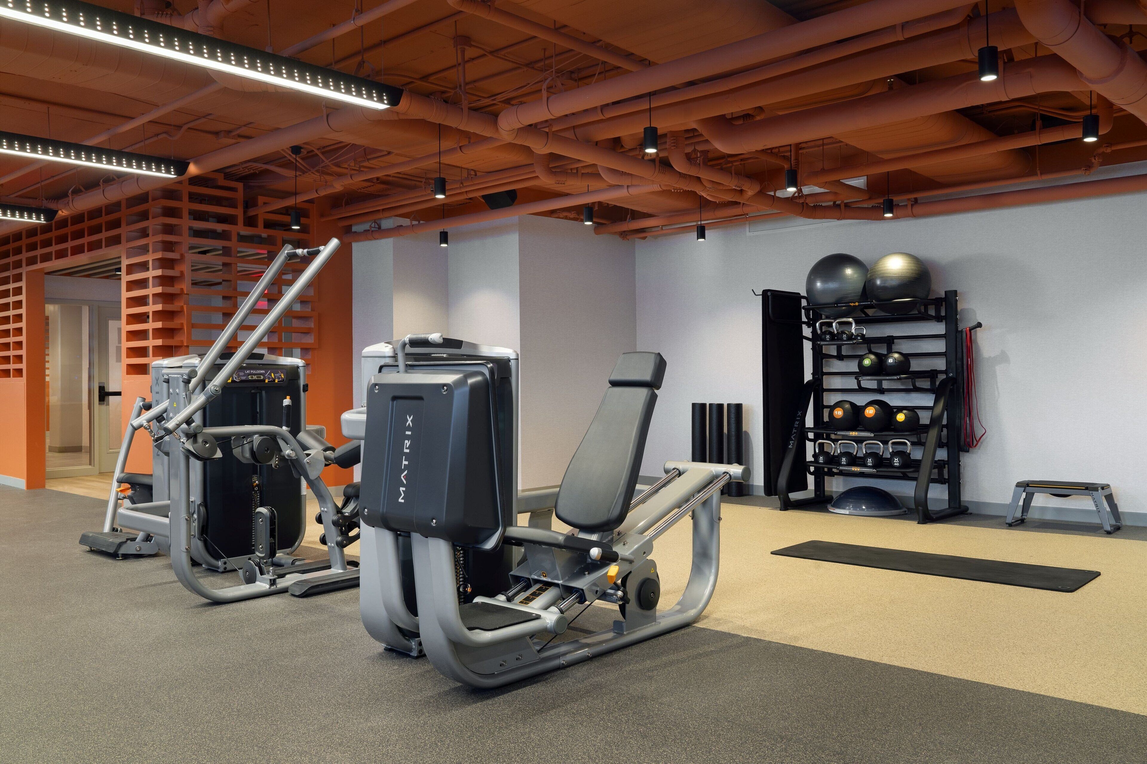 Un gimnasio con equipamiento de ejercicio, un soporte para pesas y una colchoneta de yoga.