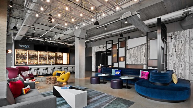 Un espace lounge moderne avec des sièges, un bar et un mur orné de motifs.