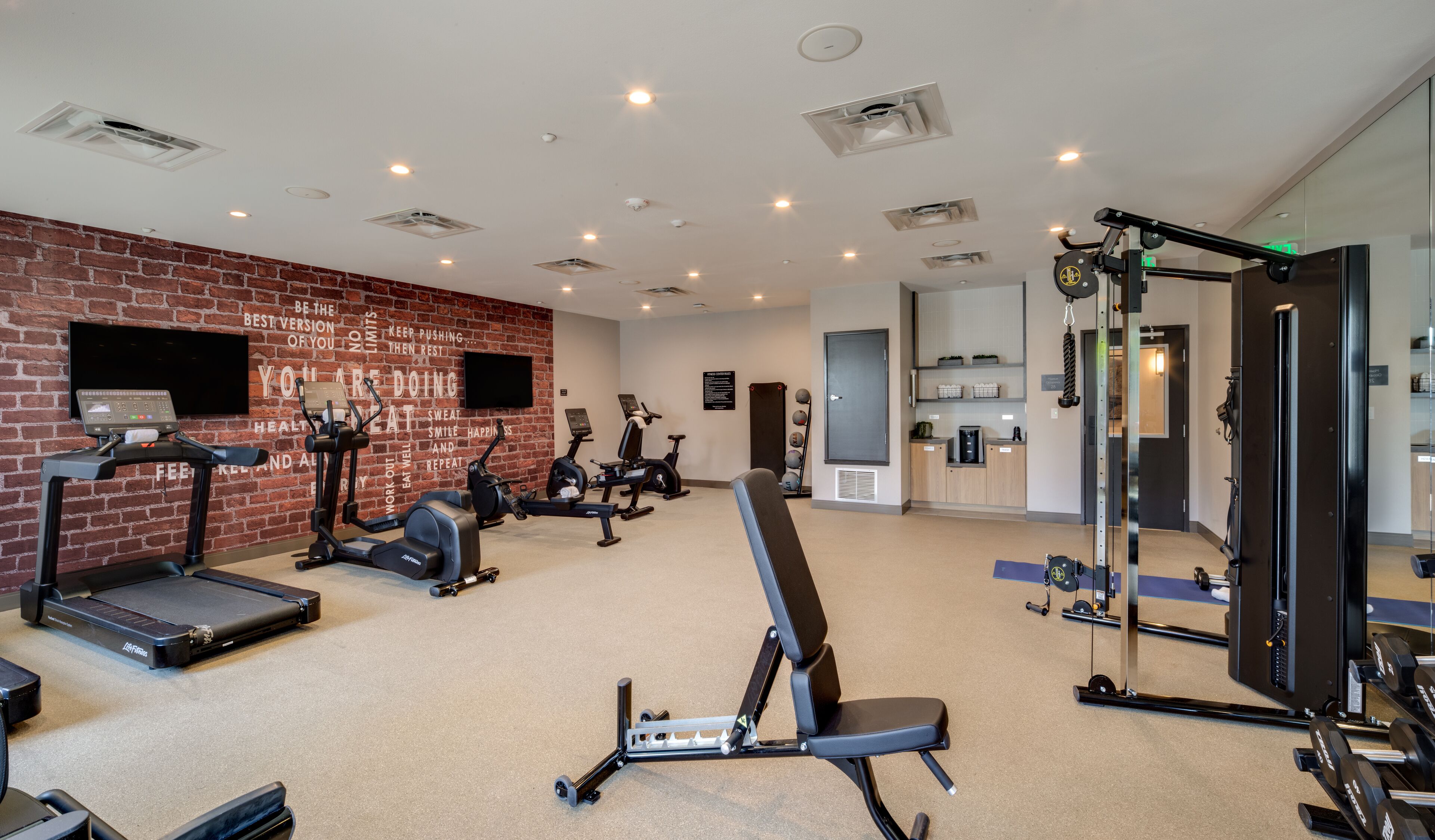 A gym with treadmills, elliptical machines, and a weight bench.