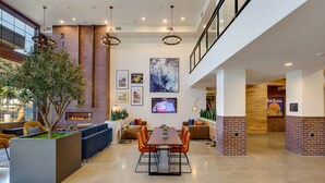 A spacious, modern interior with a dining area, seating, and a fireplace. - Ayres Hotel Rialto Fontana (Rialto)