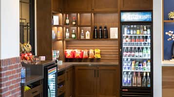 A hotel bar area with wooden cabinets, a minibar, and a beverage refrigerator.
