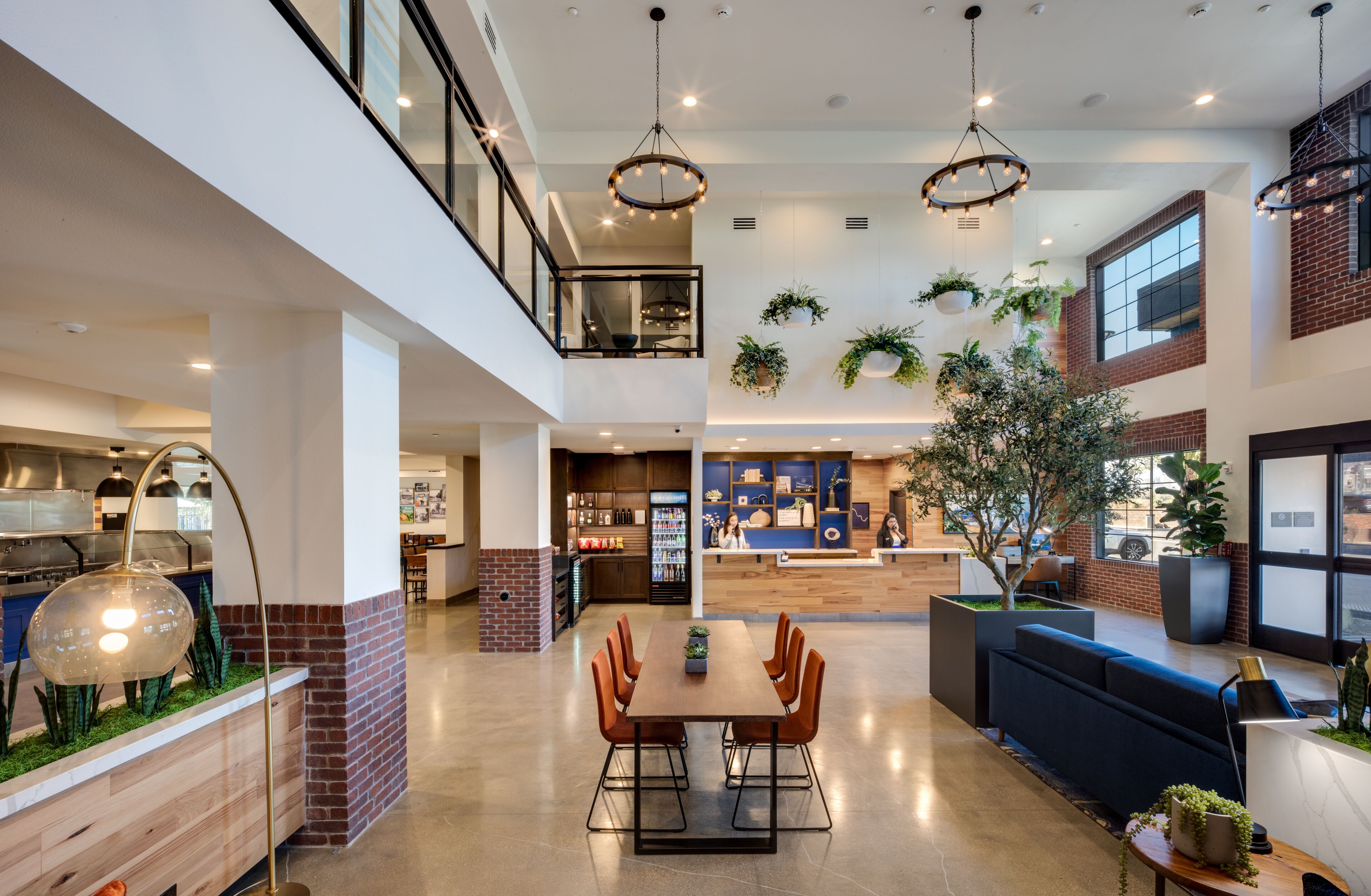 A spacious indoor area with a dining table, chairs, a sofa, and a hanging light fixture.