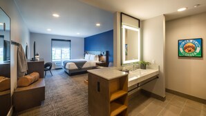 A modern hotel room with a large bed, a sitting area with a chair, a desk, a vanity with a mirror, and a bathroom with a sink and toilet. - Ayres Hotel Rialto Fontana (Rialto)