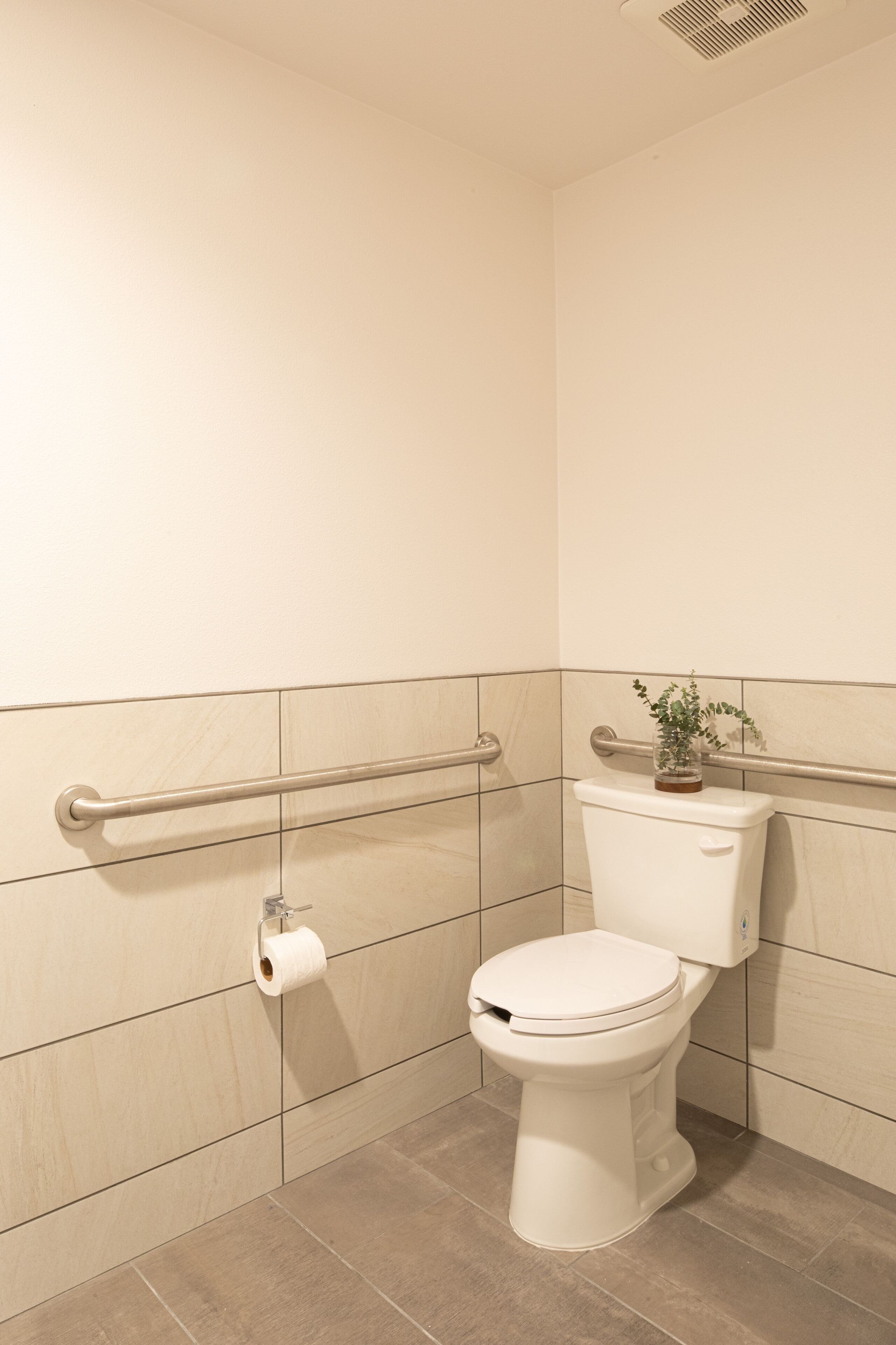 Et badeværelse med toilet, gelænder og toiletpapirholder.