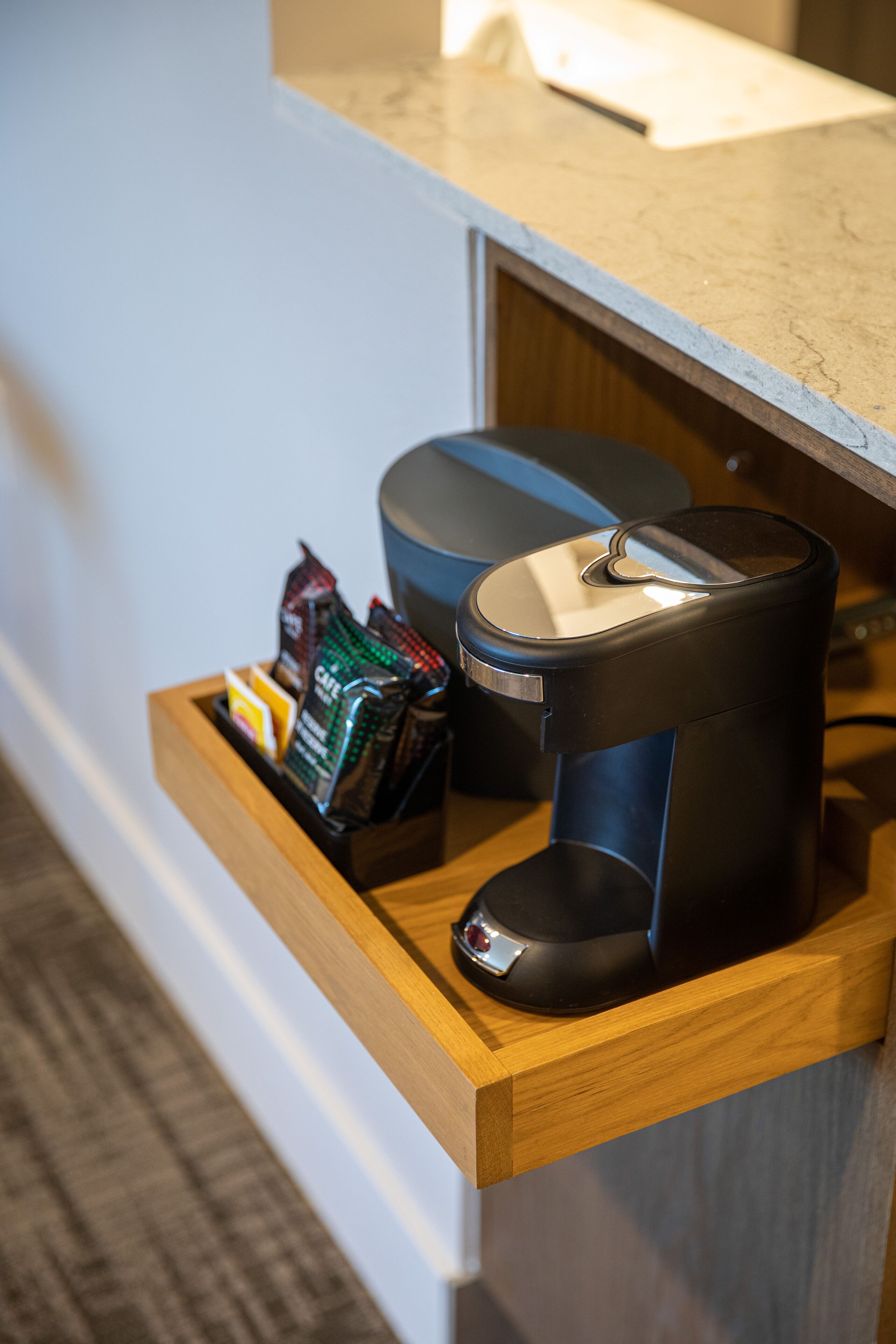 A coffee machine and a tray with coffee pods on a wooden counter.