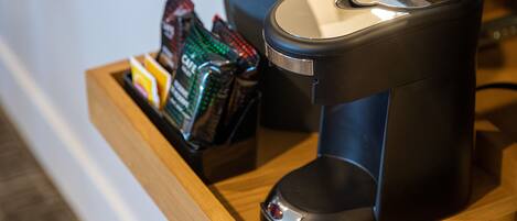 A coffee machine and a tray with coffee pods on a wooden counter.