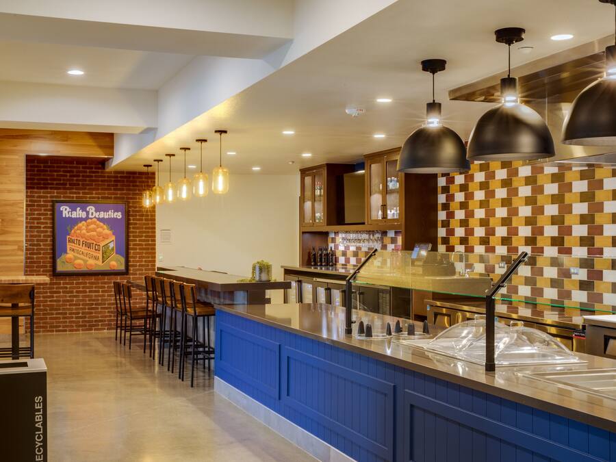 A modern kitchen area with a bar counter, hanging pendant lights, and a tiled backsplash.
