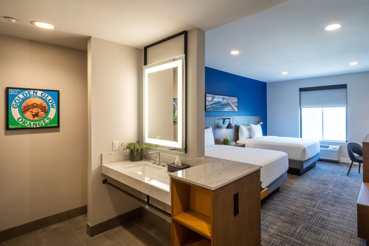 Ein Hotelzimmer mit großem Spiegel, einem Bett, einem Schreibtisch und einem Sessel.