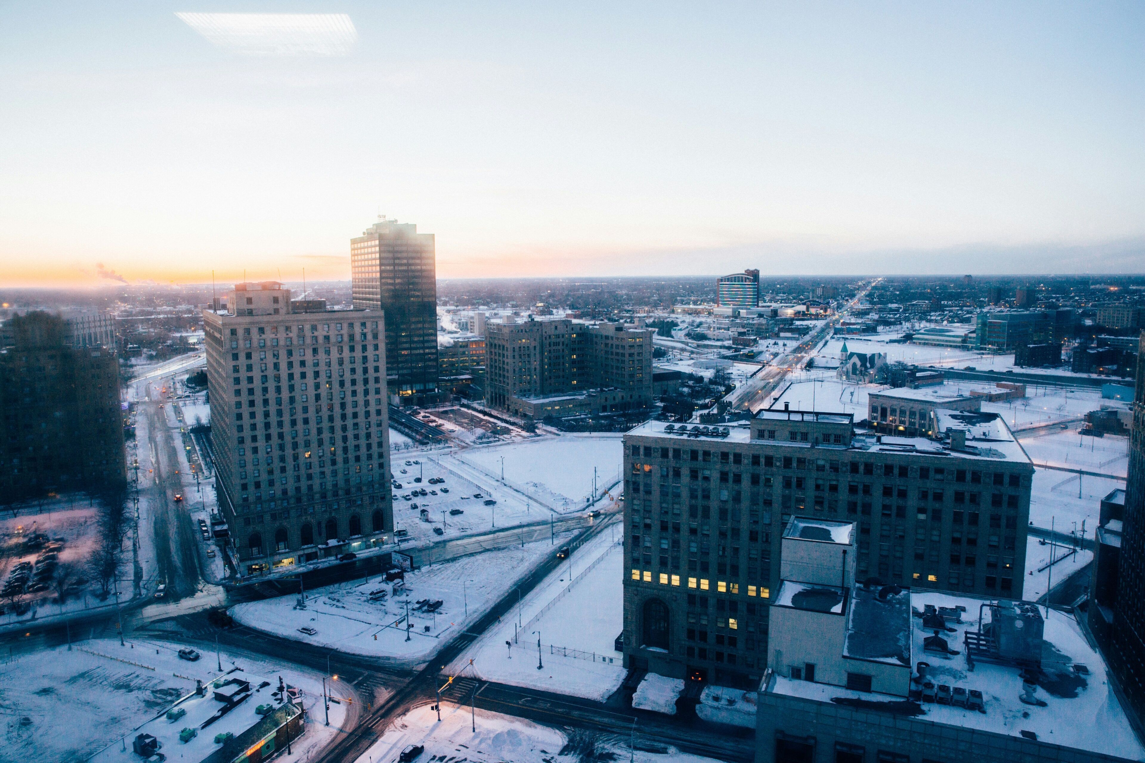 A cityscape with high-rise buildings, a snow-covered intersection, and a clear sky.