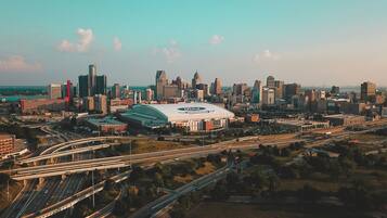 An aerial view of a cityscape with a prominent stadium, multiple highways, and a dense cluster of high-rise buildings.