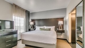 A hotel room with a large bed, a television, a desk with a lamp, and a mirror. - King Studio Close to Texas Tech (Lubbock)