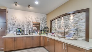 A modern kitchen with a stone backsplash, a coffee station, and a fruit display. - King Studio Close to Texas Tech (Lubbock)