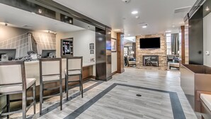 A modern hotel lobby with a reception desk, seating area, stone fireplace, and a flat-screen TV mounted on the wall. - King Studio Close to Texas Tech (Lubbock)