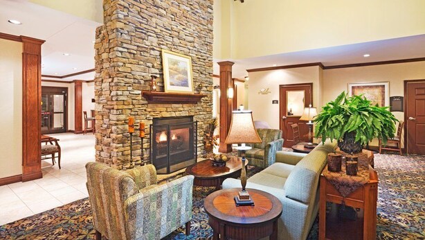 A spacious lobby with a stone fireplace, comfortable seating, and a large plant. - Studio | Free Breakfast. Indoor Pool & Gym. (Oak Ridge)