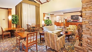 A hotel lobby with a dining area, sofas, a bar, and a kitchen in the background. - Studio | Free Breakfast. Indoor Pool & Gym. (Oak Ridge)