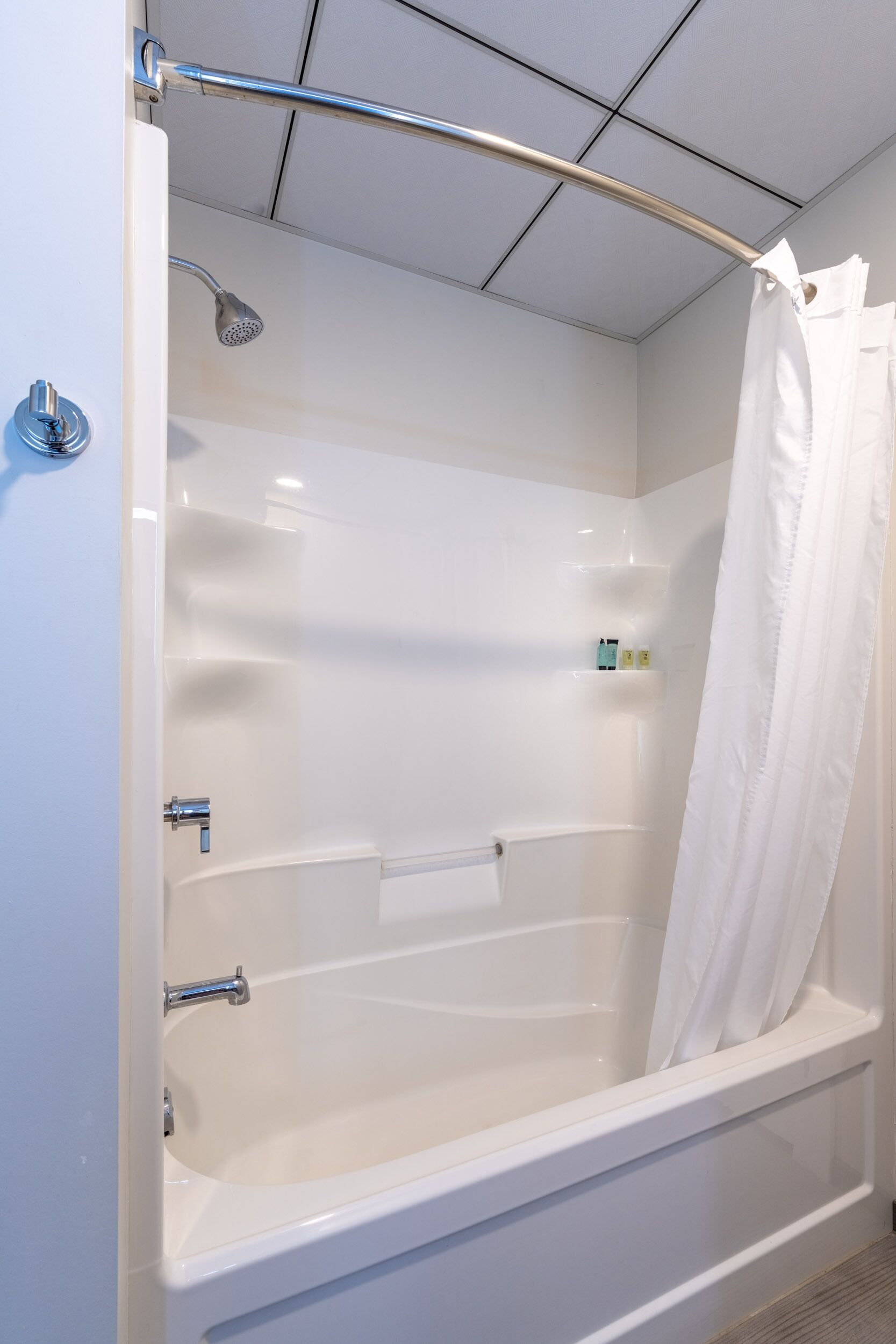 Une salle de bain moderne avec une baignoire blanche, une pomme de douche et une paroi de douche en verre.