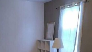 Une chambre à coucher avec un lit, une table de chevet, une lampe et une fenêtre avec des rideaux.