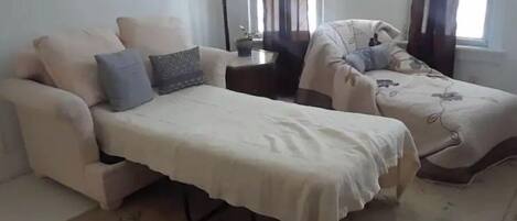 A room with two sofas, a small table, and a lamp.