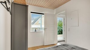 Un dormitorio con cama, armario, ventana y puerta que da a un espacio exterior.