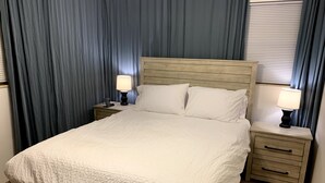 A neatly made bed with a white quilt, two bedside tables with lamps, and a headboard. - Charming Updated & Pet-Friendly Ranch Close to Beaches, Baseball, and Downtown  (Sarasota)