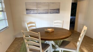A dining area with a round wooden table, white chairs, and a green patterned rug. - Charming Updated & Pet-Friendly Ranch Close to Beaches, Baseball, and Downtown  (Sarasota)