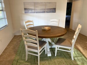 Enjoy meals in this dining area with a round table and four chairs, surrounded by framed artworks and a patterned rug.