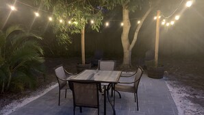 An outdoor patio with a table and chairs, surrounded by trees and string lights. - Charming Updated & Pet-Friendly Ranch Close to Beaches, Baseball, and Downtown  (Sarasota)