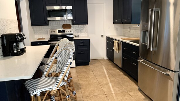 A modern kitchen with dark cabinets, stainless steel appliances, and a white countertop. - Charming Updated & Pet-Friendly Ranch Close to Beaches, Baseball, and Downtown  (Sarasota)