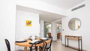 A dining area with a round wooden table, black chairs, and a small console table with drawers. - Blue Pearl 206 by Avecoeur (Nice)